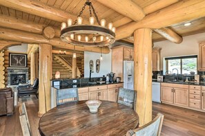 A rustic interior with a wooden dining table, a fireplace, and a kitchen area. - 4 BR Luxury Lakefront Cabin w/ Mtn Views (Lake County)