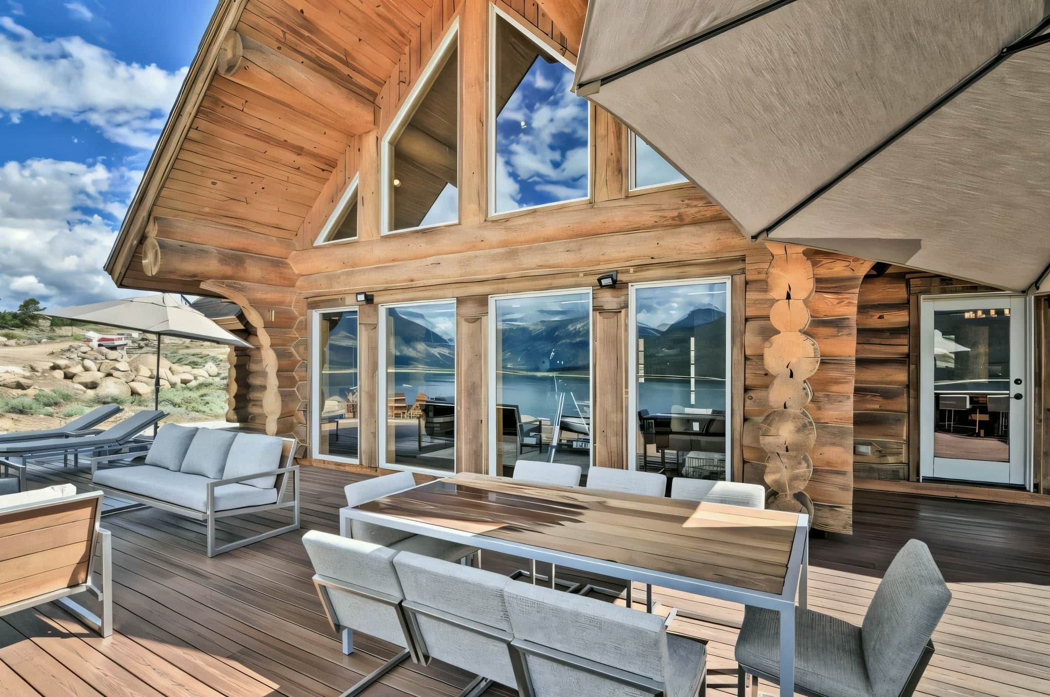 A wooden cabin with a deck, large windows, and outdoor seating.