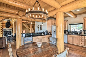 A log cabin interior with a dining area, kitchen, and fireplace.