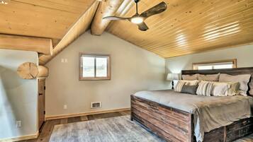 Una camera da letto con soffitto spiovente, un letto con testiera in legno, una ventola a soffitto e una finestra.