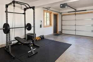 Une salle de sport à domicile équipée d’un support à squats, d’un banc et de disques de poids.