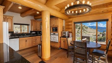 Una cocina moderna con armarios de madera, una isla central y vistas a un paisaje montañoso a través de amplios ventanales.