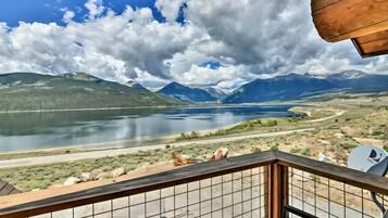 A balcony with a view of a lake, mountains, and a clear sky.