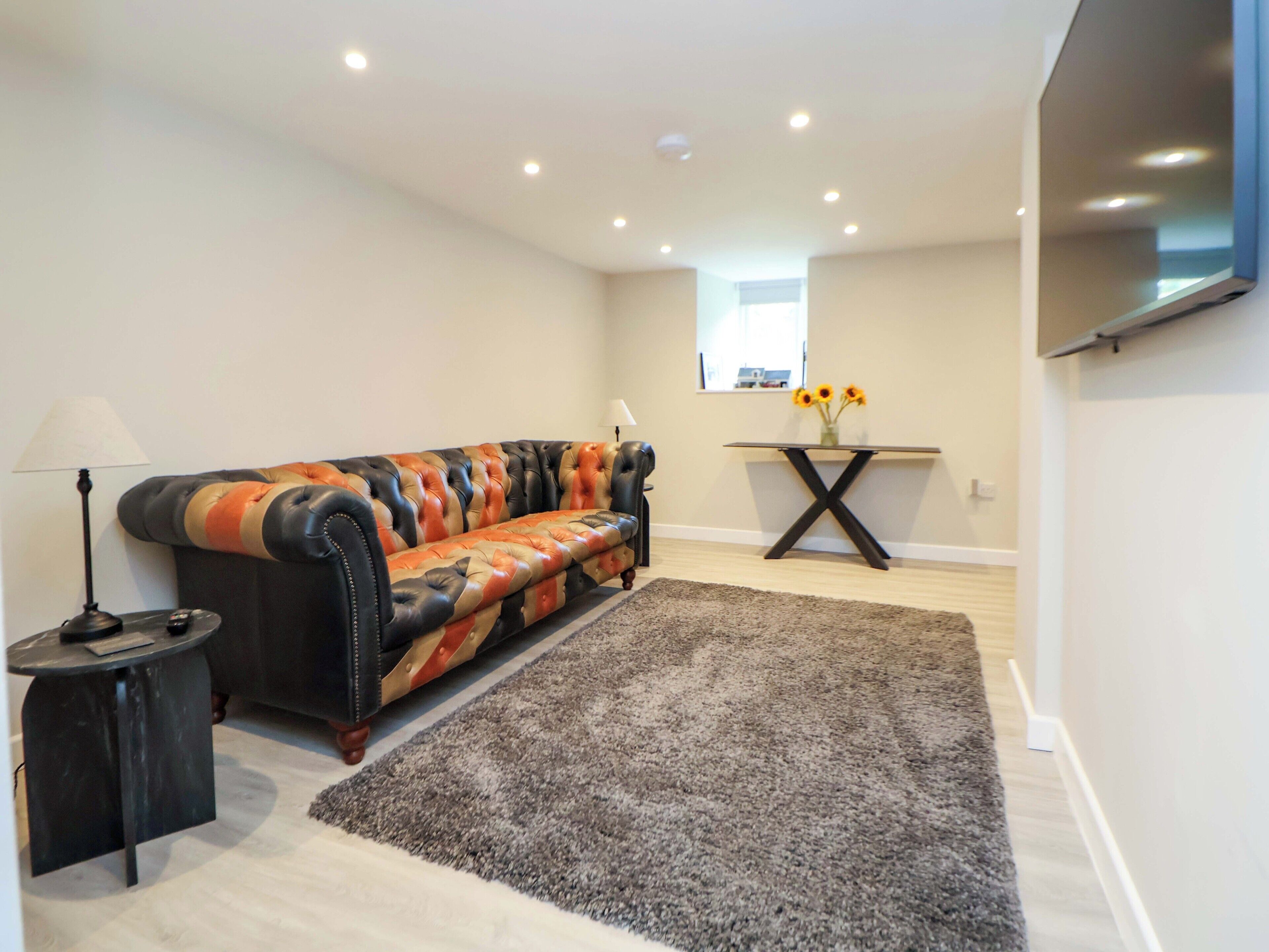 A modern living room with a leather sofa, a small side table, a coffee table, and a rug.