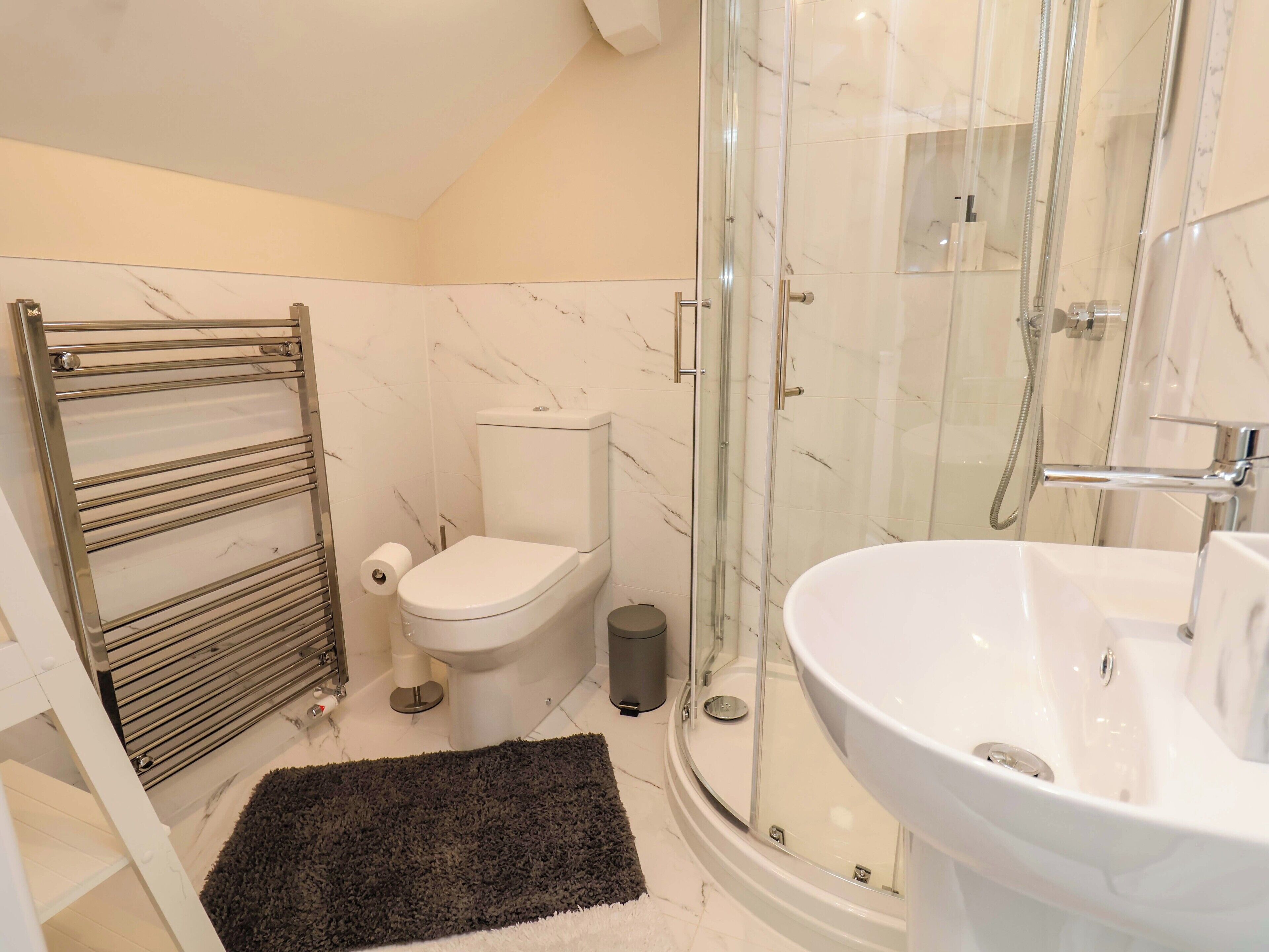 A modern bathroom with a glass-enclosed shower, a white toilet, and a large white sink.
