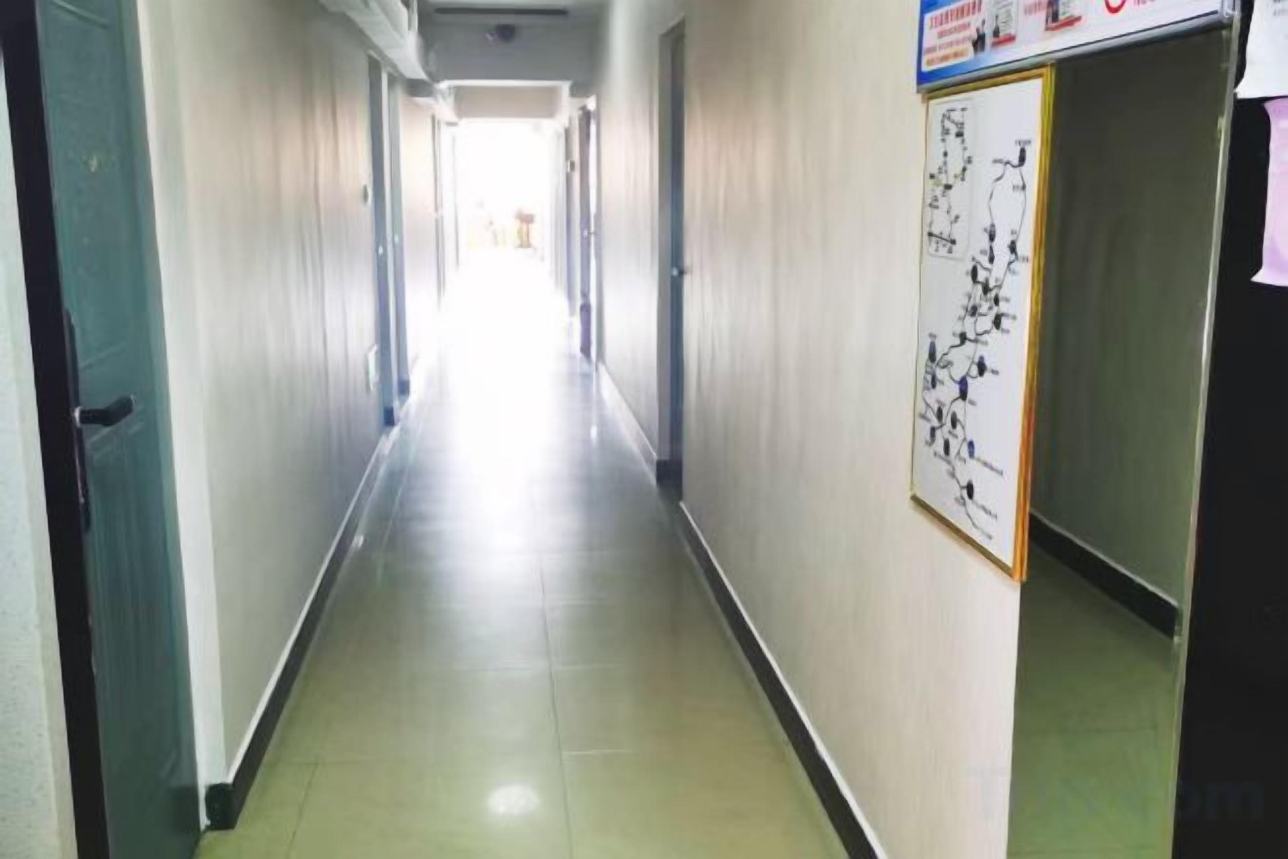 A long, narrow hallway with doors on both sides, leading to rooms.