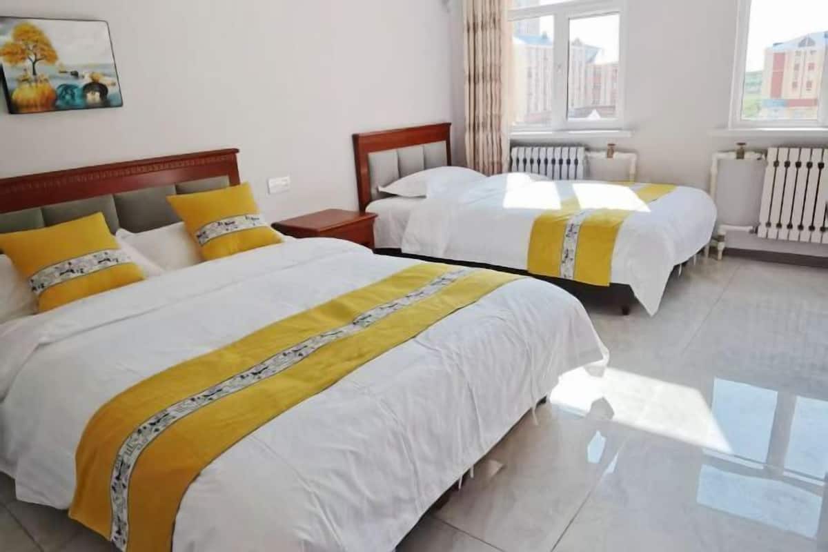 Habitación de hotel con dos camas, una mesita de noche, una ventana con cortinas y un radiador.