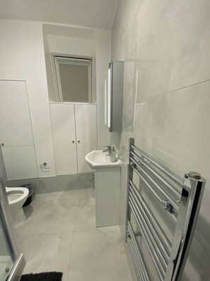 Un bagno moderno con lavandino bianco, specchio e cabina doccia in vetro.