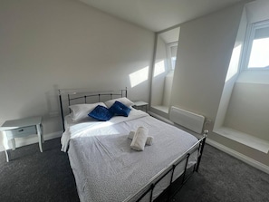 Et soveværelse med seng, et natbord, en radiator og et vindue.
