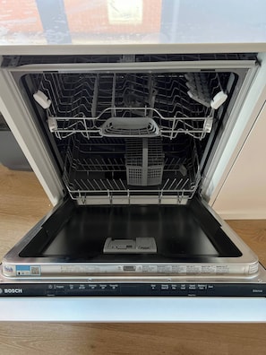 An open Bosch dishwasher with multiple racks and a control panel.