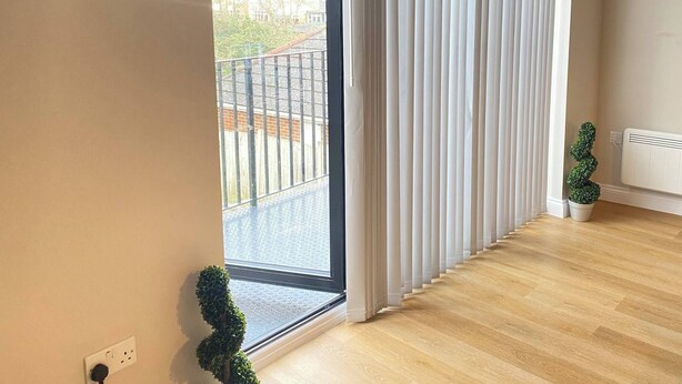 A room with a large sliding glass door leading to a balcony, a radiator, and a potted plant. - Charming 2-bedroom Apartment in the Heart of Beckenham (Beckenham)