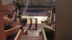 A residential building with a pool area, a staircase leading to a balcony, and a clear view of the surrounding neighborhood. - ORLANDO COSTA ADEJE (Costa Adeje)