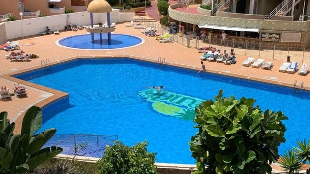 A swimming pool with a sun-shaped water feature, surrounded by lounge chairs and a poolside bar. - ORLANDO COSTA ADEJE (Costa Adeje)