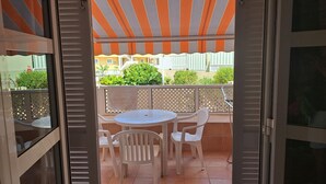 An open balcony with a table and chairs, a view of buildings, and a striped awning. - ORLANDO COSTA ADEJE (Costa Adeje)