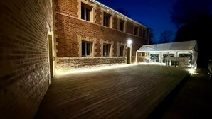 A brick building with a wooden deck and a white tent-like structure. - La Laiterie Gite de groupe Proix (Proix)