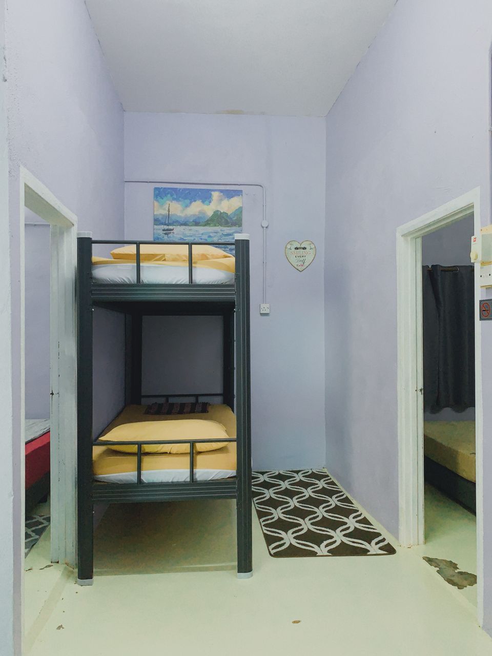 Une chambre avec des lits superposés, un tableau représentant un voilier au mur et un panneau en forme de cœur.