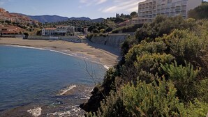 Un hotel costero con vistas al mar y montañas al fondo.