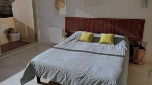 Un dormitorio con cama, dos almohadas, un radiador y una ventana.