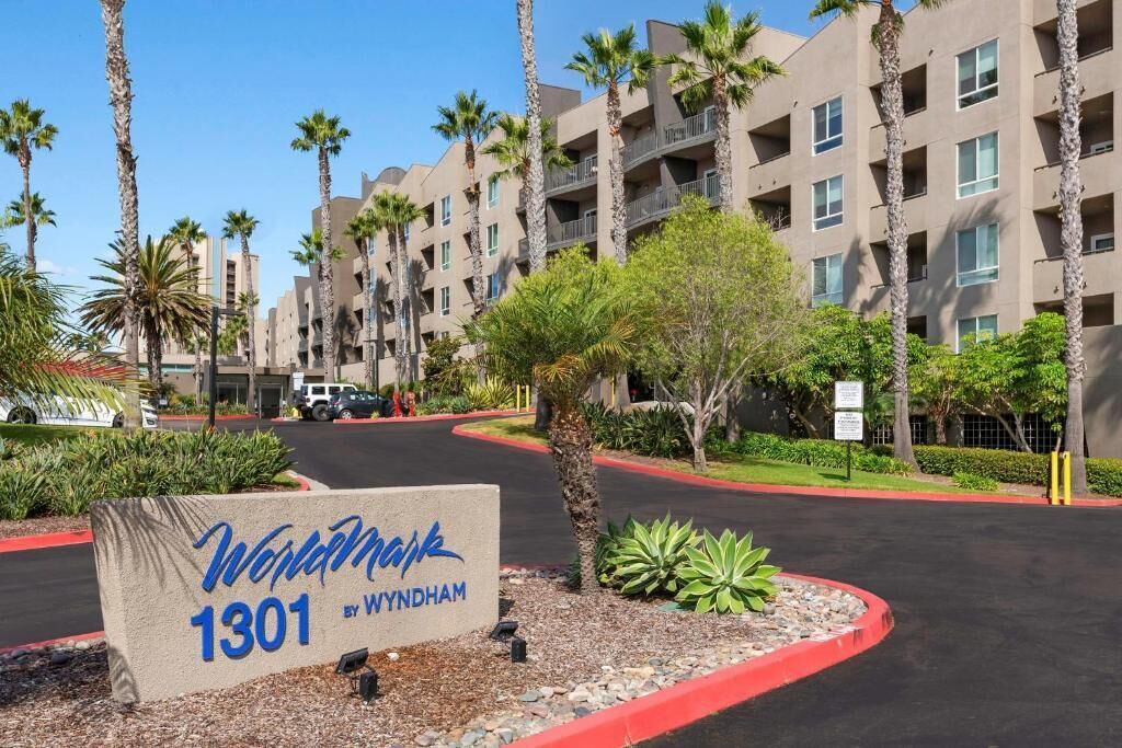 Ein Hotel Eingang mit einem Schild, auf dem 'WorldMark 1301 by Wyndham' steht, umgeben von Palmen und einem Parkplatz.