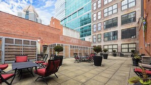An outdoor patio area with tables and chairs, surrounded by buildings.