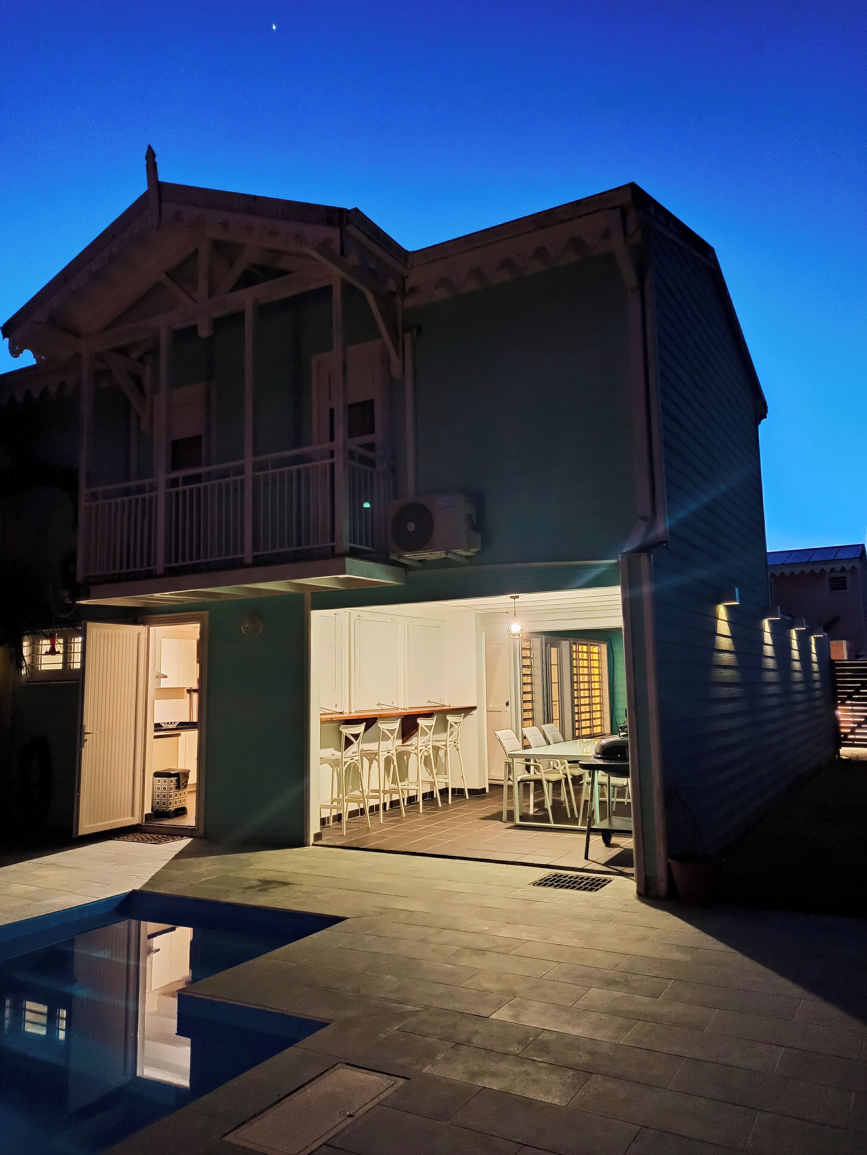 A two-story house with a balcony, a dining area, and a small pool.