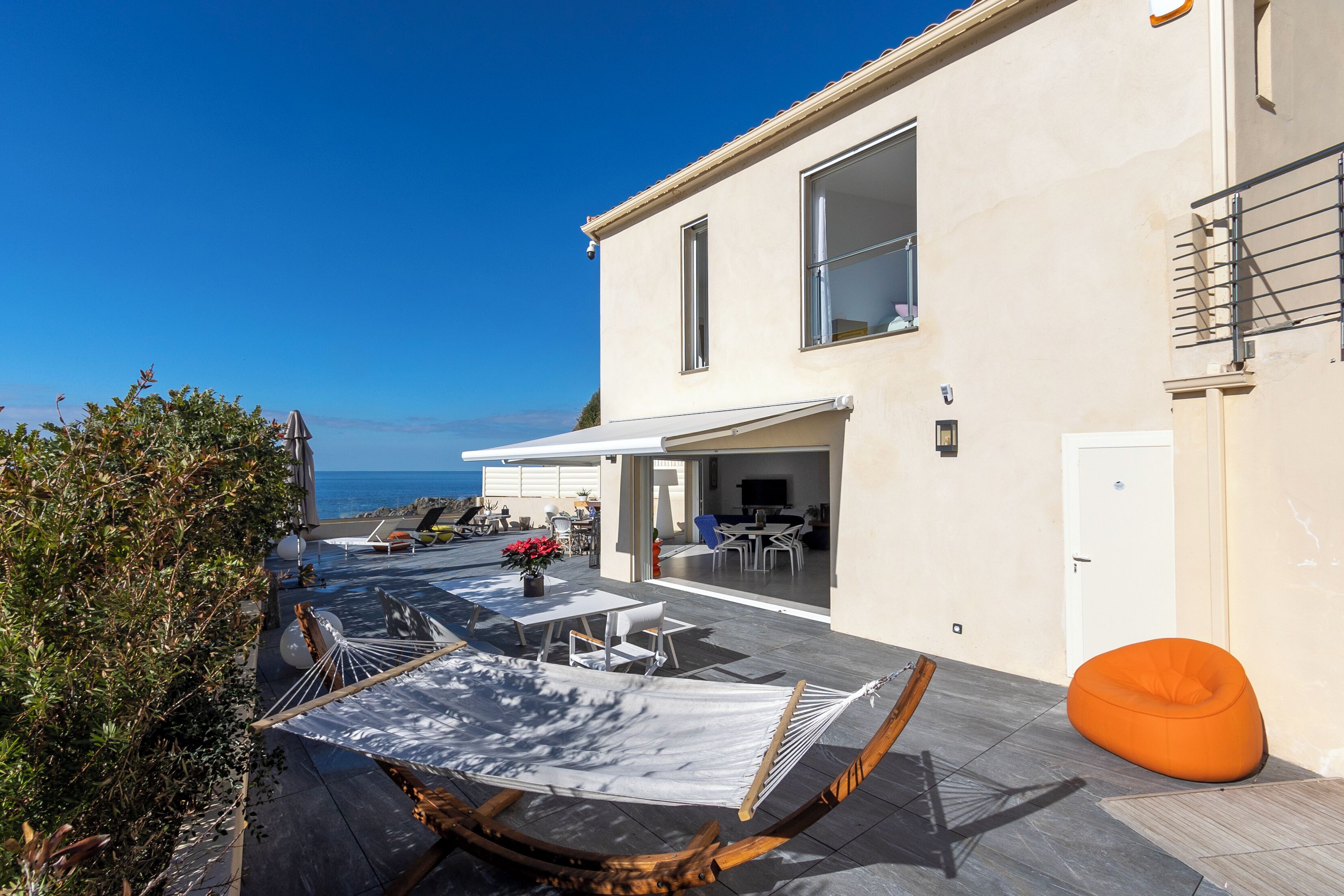 A modern house with a patio, outdoor furniture, and a view of the sea.