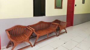 A hallway with three wooden benches, a red door, and a window with a green framed item on the wall. - Hotel O Selesa Inn (Kuala Berang)