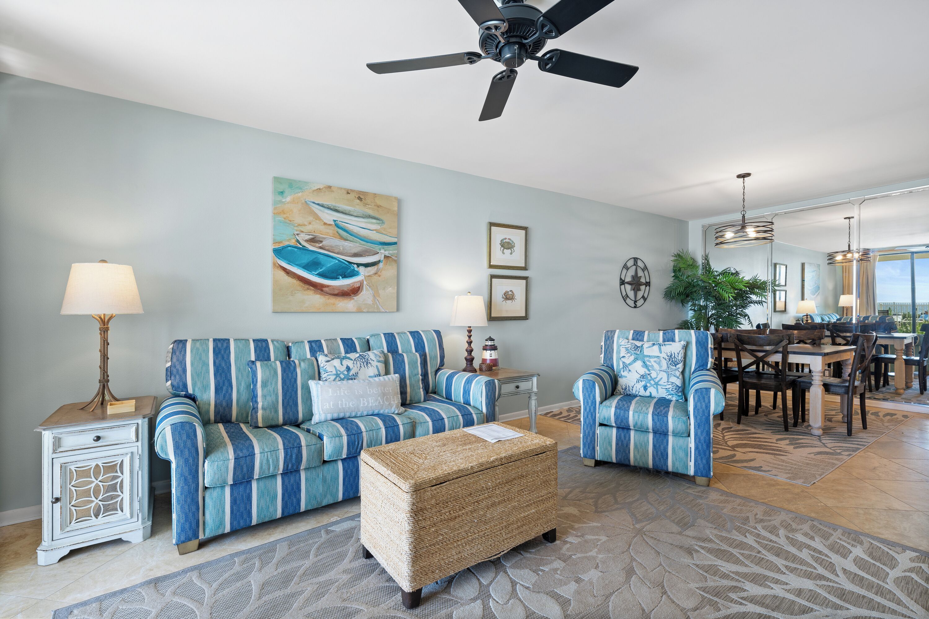 A living room with striped sofas, a coffee table, and a ceiling fan.