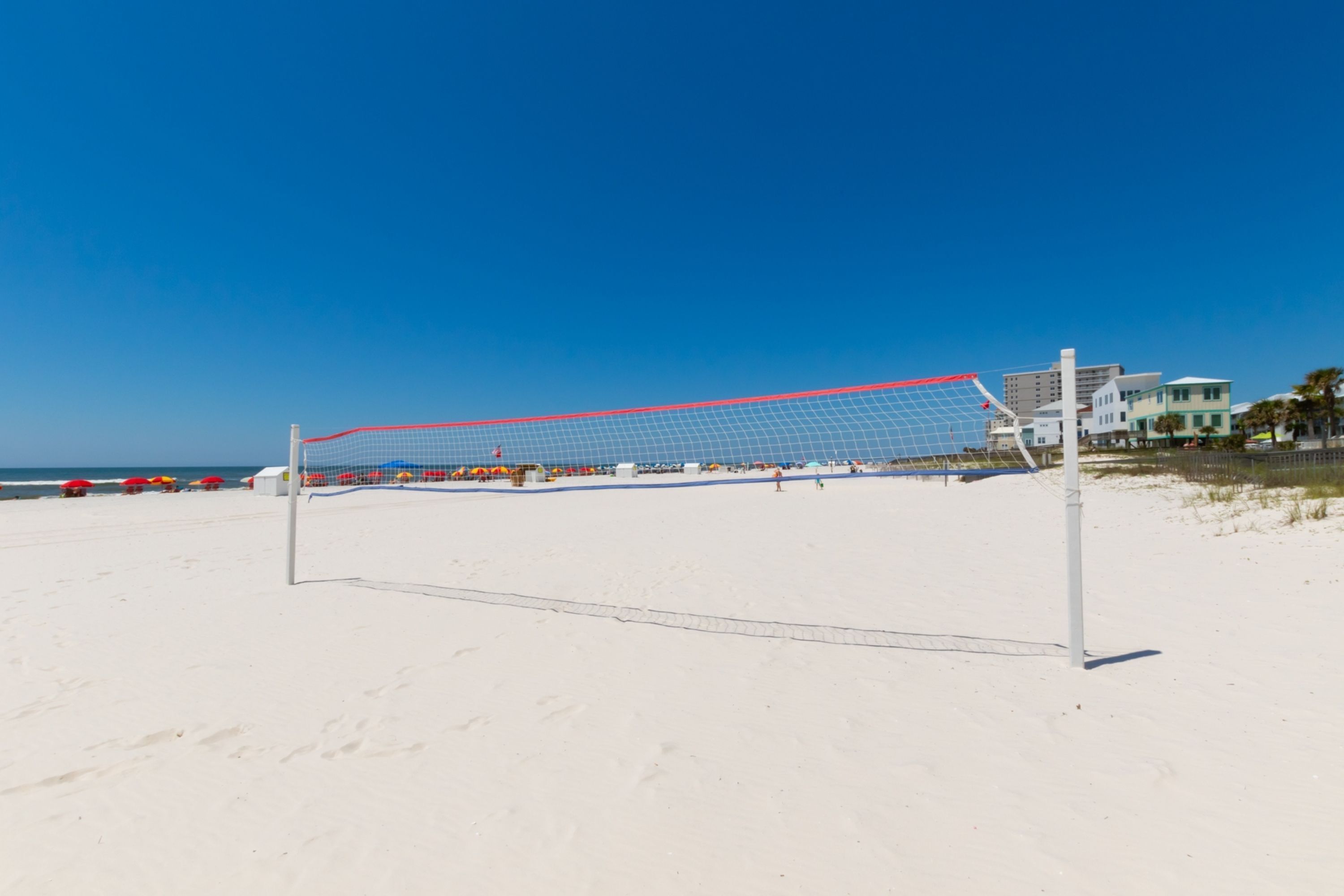 Una red de voleibol de playa en una arena con cielo azul despejado.