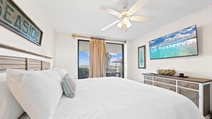 Een hotelkamer met een groot bed, een plafondventilator, een televisie en uitzicht op de omgeving.