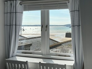 Una habitación con un gran ventanal con vistas a una playa y al mar.