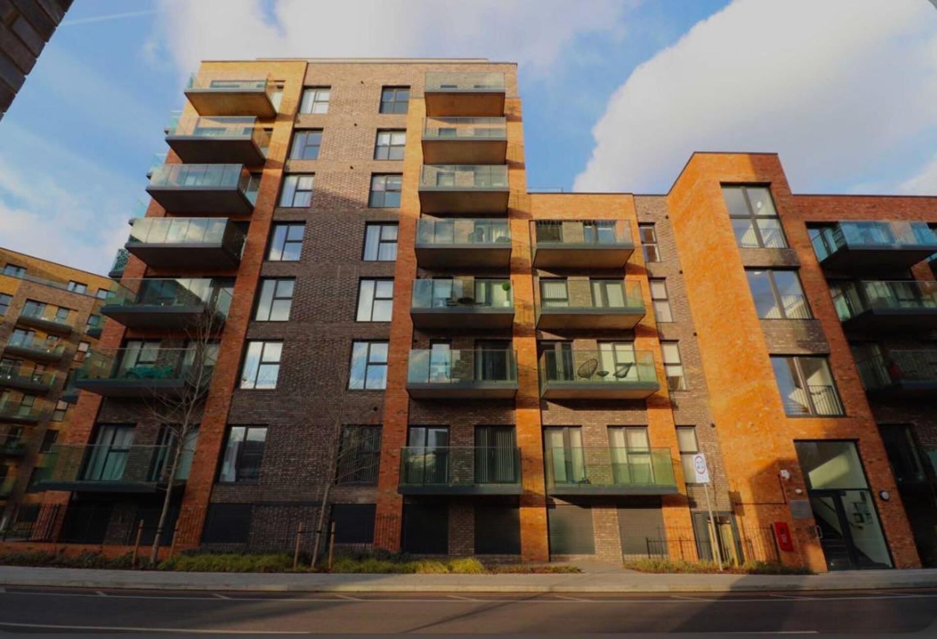 A multi-story residential building with a brick facade, large windows, and balconies.