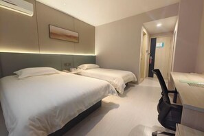 Ein Hotelzimmer mit zwei Betten, einem Schreibtisch und einem Stuhl.