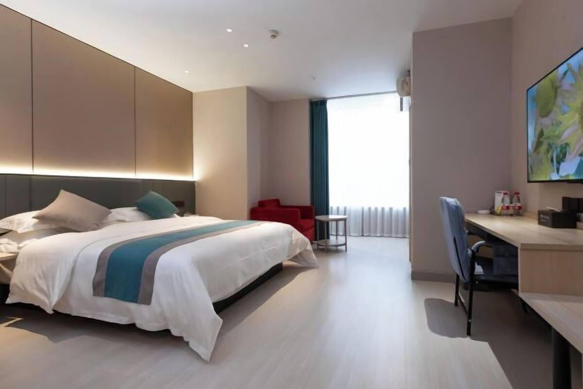 A modern hotel room with a large bed, a desk, and a chair.