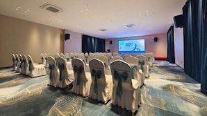 A conference room with rows of chairs, a projector screen, and a carpeted floor. - Hehuaju Hotel (Chuzhou Suning Plaza) (Chuzhou)