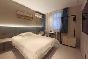 Ein modernes Hotelzimmer mit einem großen Bett, einem Schreibtisch, einem Sessel und einem Kleiderschrank.