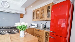 Una cocina con un refrigerador rojo, armarios de madera, un microondas y una estufa a gas.