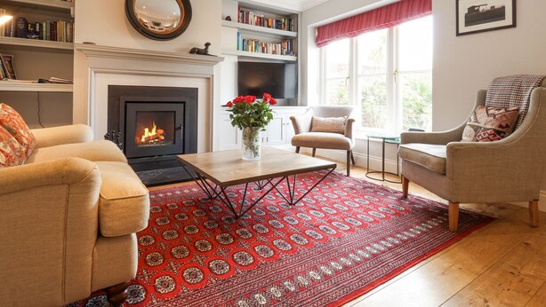 Una sala de estar con chimenea, sofás, una mesa de centro y una alfombra estampada.