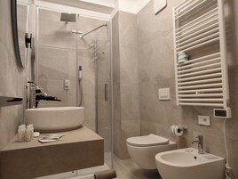 A modern bathroom with a glass-enclosed shower, a standalone sink, and a toilet.