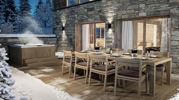Un área de comedor al aire libre con pared de piedra, mobiliario de madera y un jacuzzi.