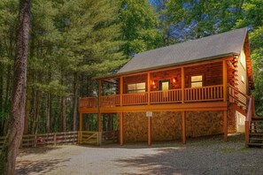 A two-story log cabin with a balcony, surrounded by a forest. - Hocking Creek Reserve | Fenced Yard, Pet Friendly (Logan)