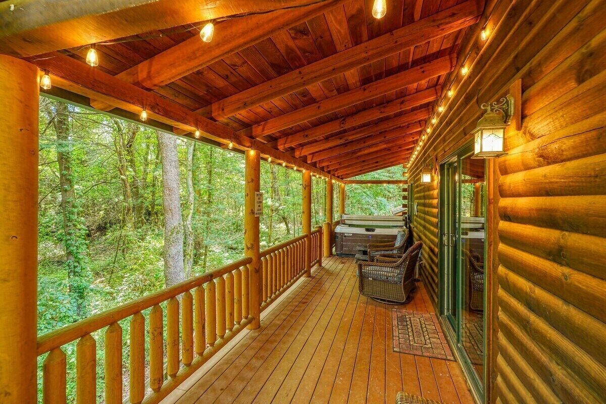 A wooden deck with a railing, a glass door, and a bench.