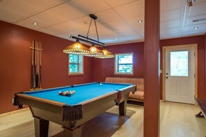 A pool table with a hanging light fixture, a sofa, and a door with a window. - Hocking Creek Reserve | Fenced Yard, Pet Friendly (Logan)