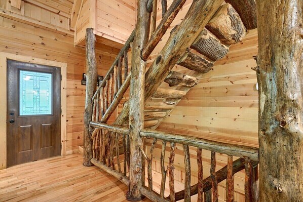 A wooden staircase with a rustic design, a wooden door with a window, and a wooden floor. - Buckeye Trail | Hocking Hills, 5BR, Hot Tub, Pets (Rockbridge)