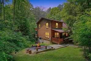 A log cabin with a porch, a fire pit, and a small deck. - Buckeye Trail | Hocking Hills, 5BR, Hot Tub, Pets (Rockbridge)