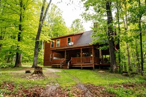 A cabin with a porch, surrounded by trees. - Bear Crossing | Hocking Hills, Sleeps 10, Pets (Logan)