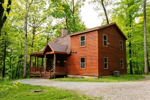 Eine Blockhütte mit Veranda, Schornstein und mehreren Fenstern.