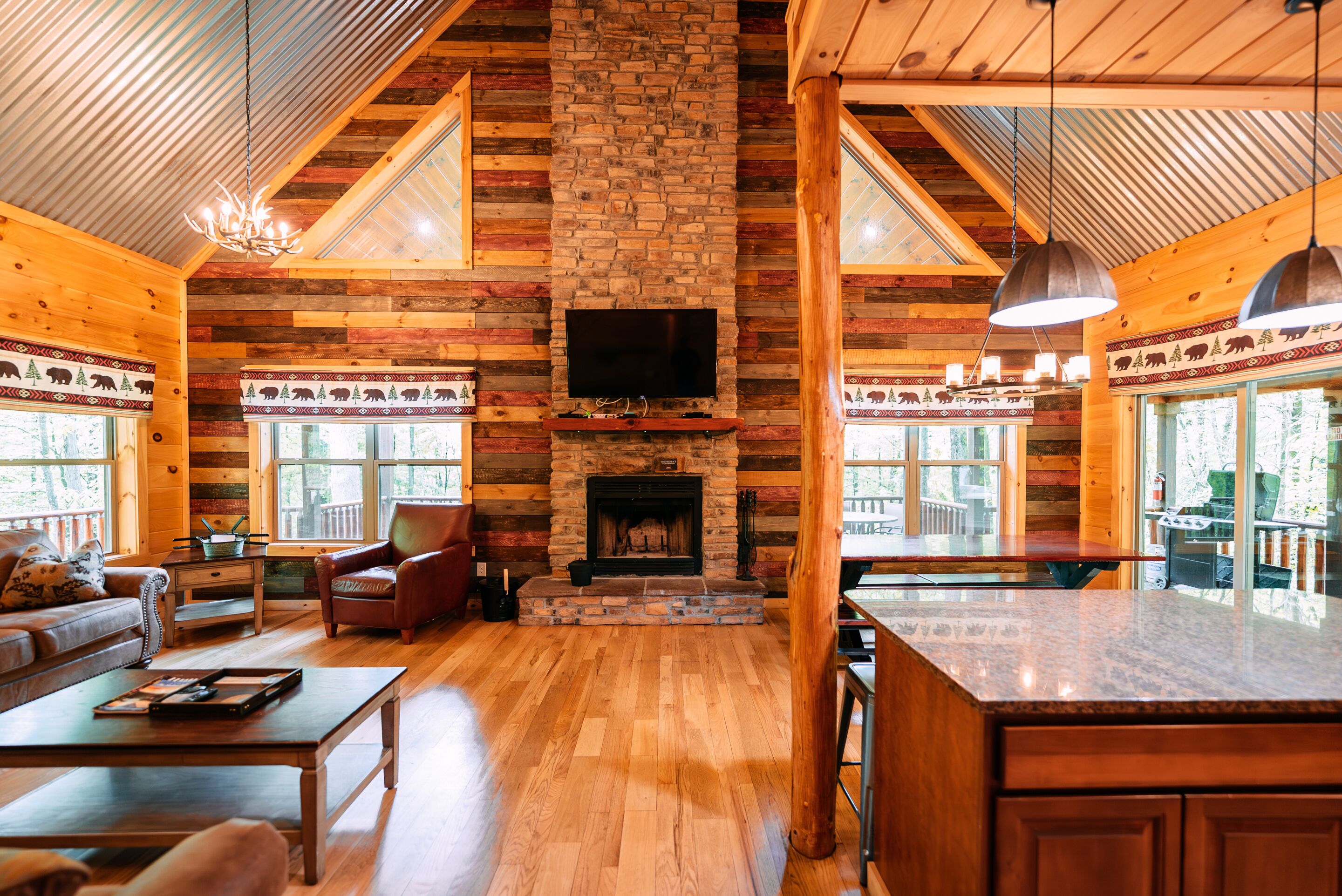 A log cabin interior with a fireplace, wooden walls, a sofa, and a dining area.