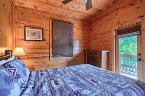 Relax in this charming bedroom with a large bed and a window with blinds, ceiling fan, and access to an outdoor area.