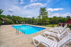 A swimming pool with lounge chairs and a fenced area.
